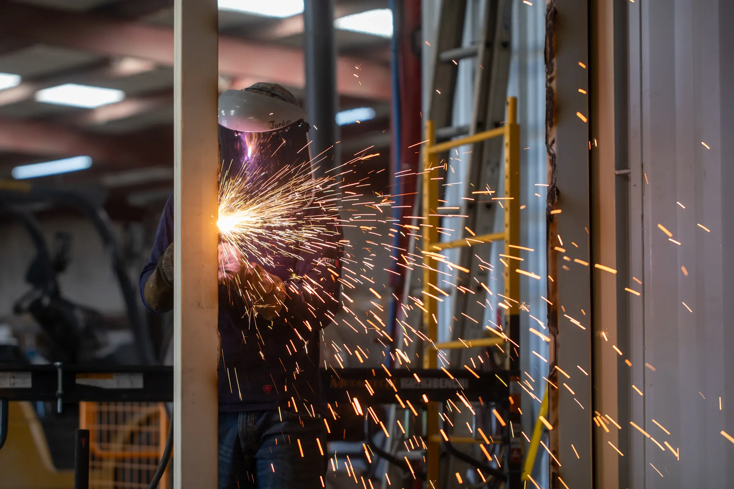 A welder at work, with sparks in the foreground